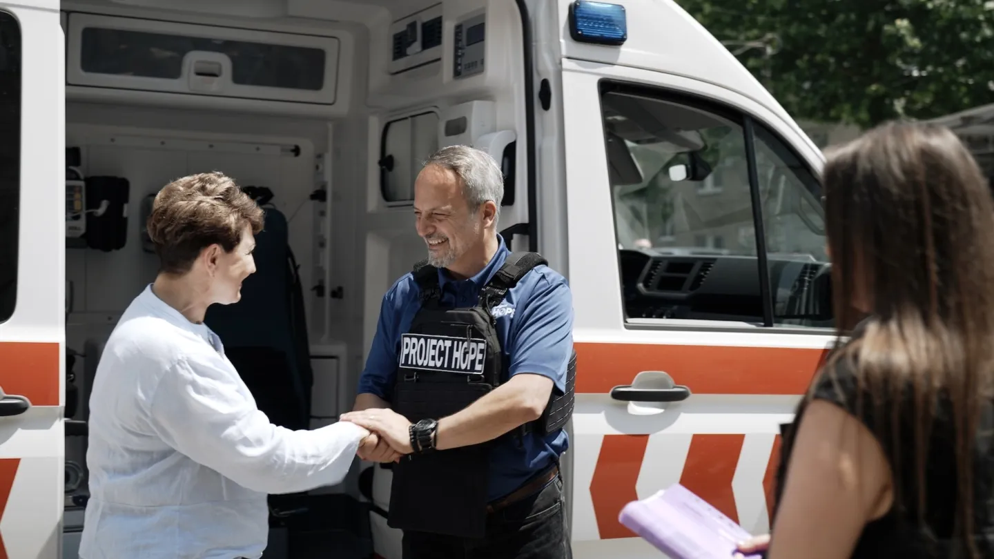 Man in safety vest shakes hand of woman