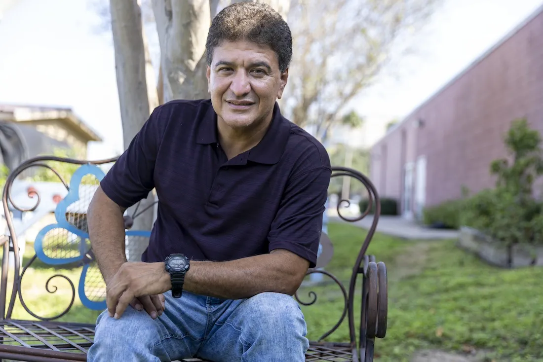 man sits on bench and smiles to camera