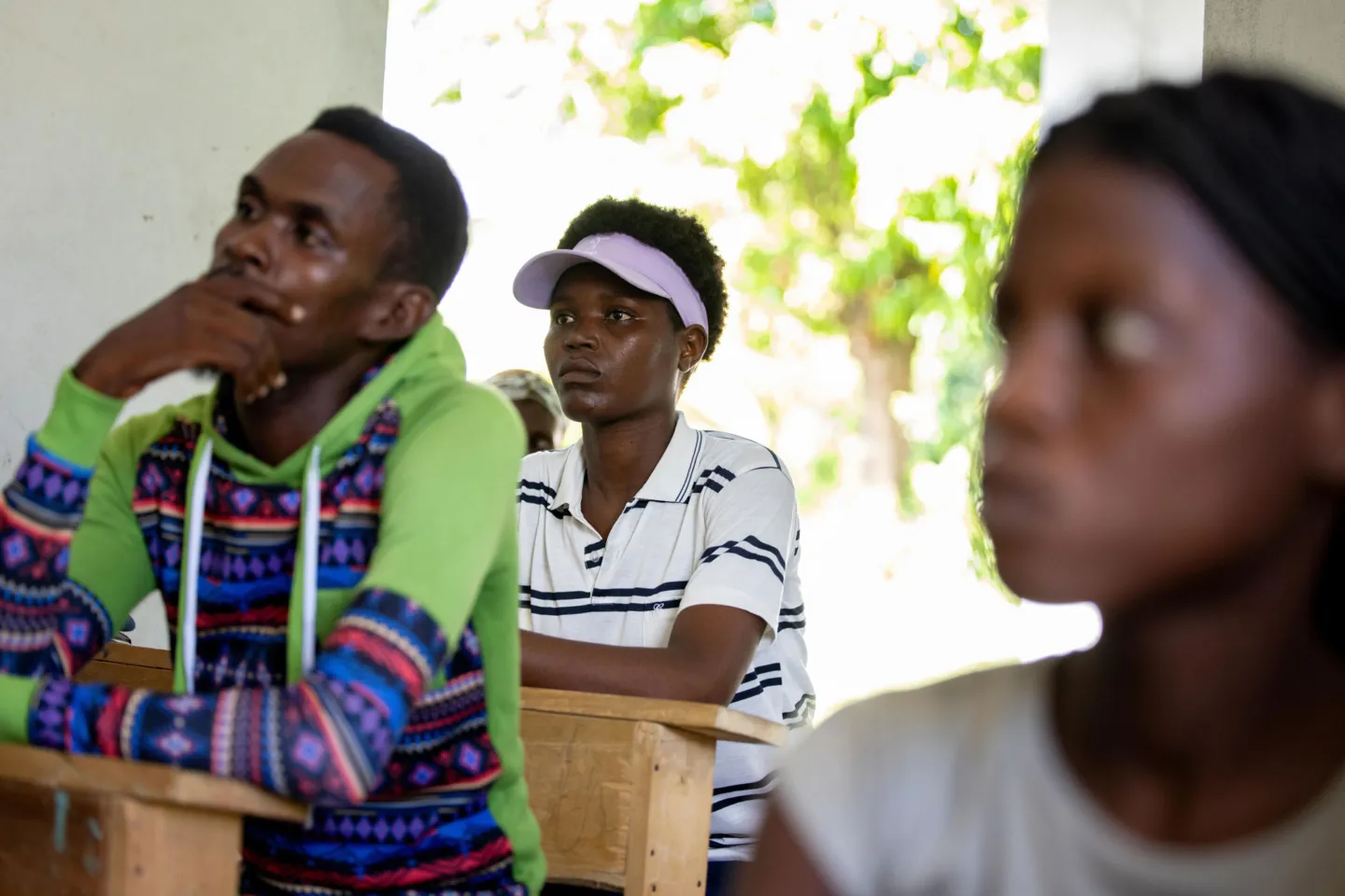 three people sitting at desks during a lesson