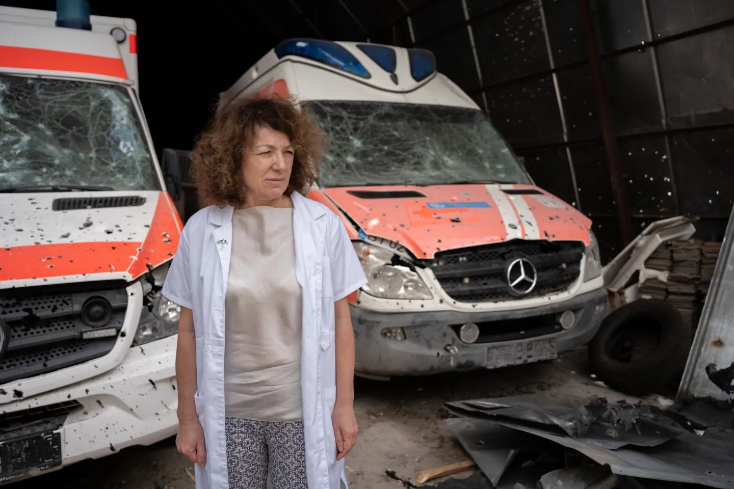 woman stands in front of destroyed ambulances in Ukraine