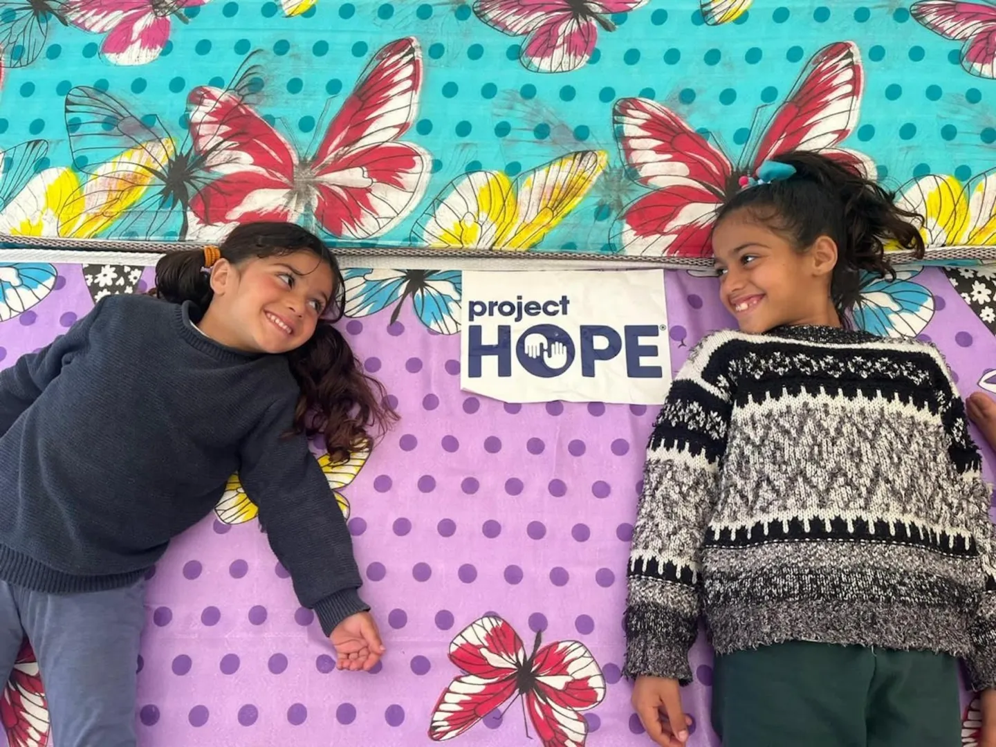 two young girls laying on mattresses
