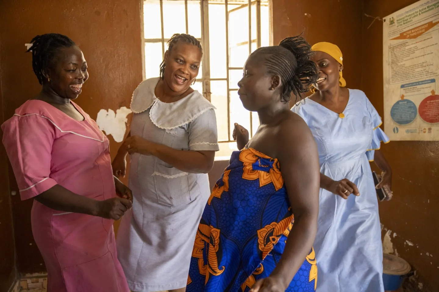 Three midwives singing and dancing with pregnant woman going through labor to help with the pains in Sierra Leone