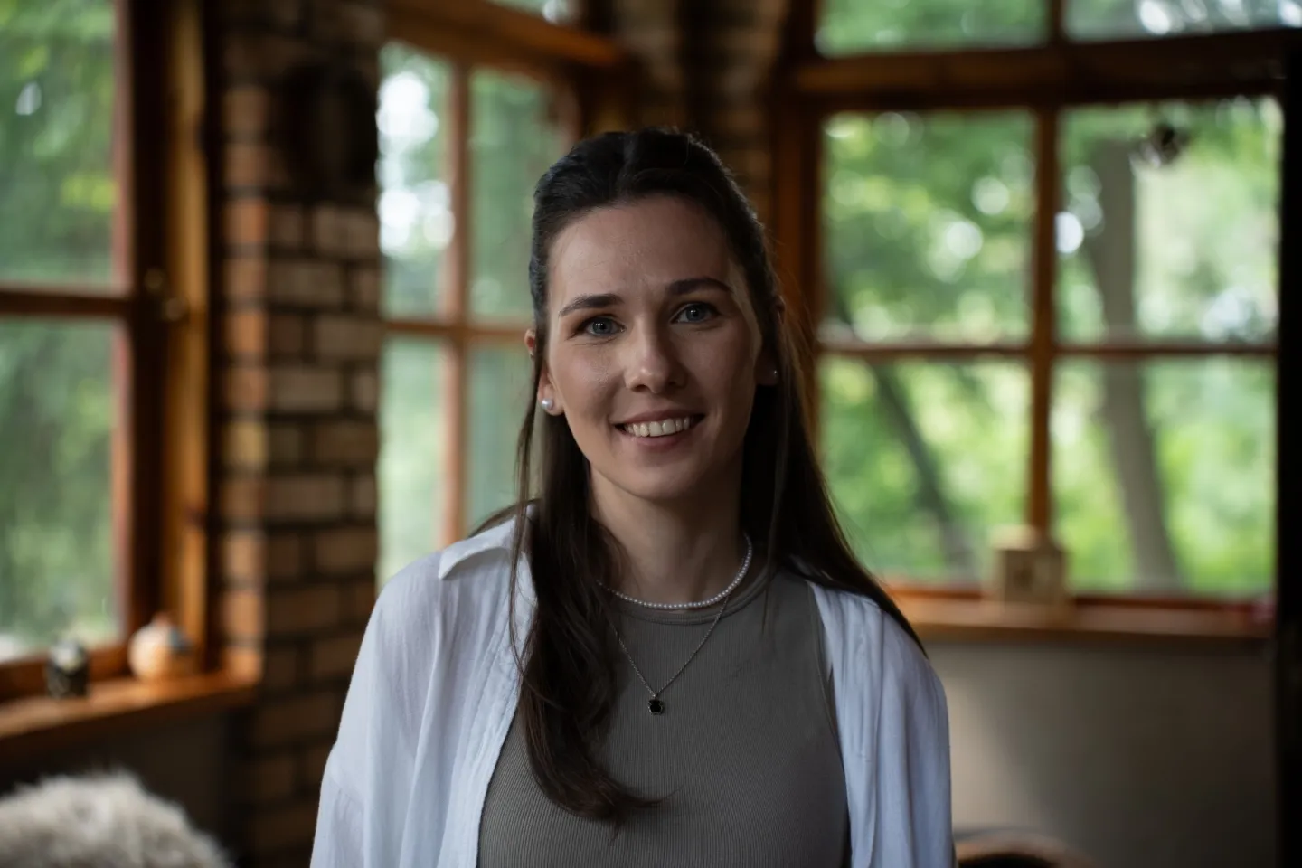 woman smiling towards camera with white blouse and tan shirt on.