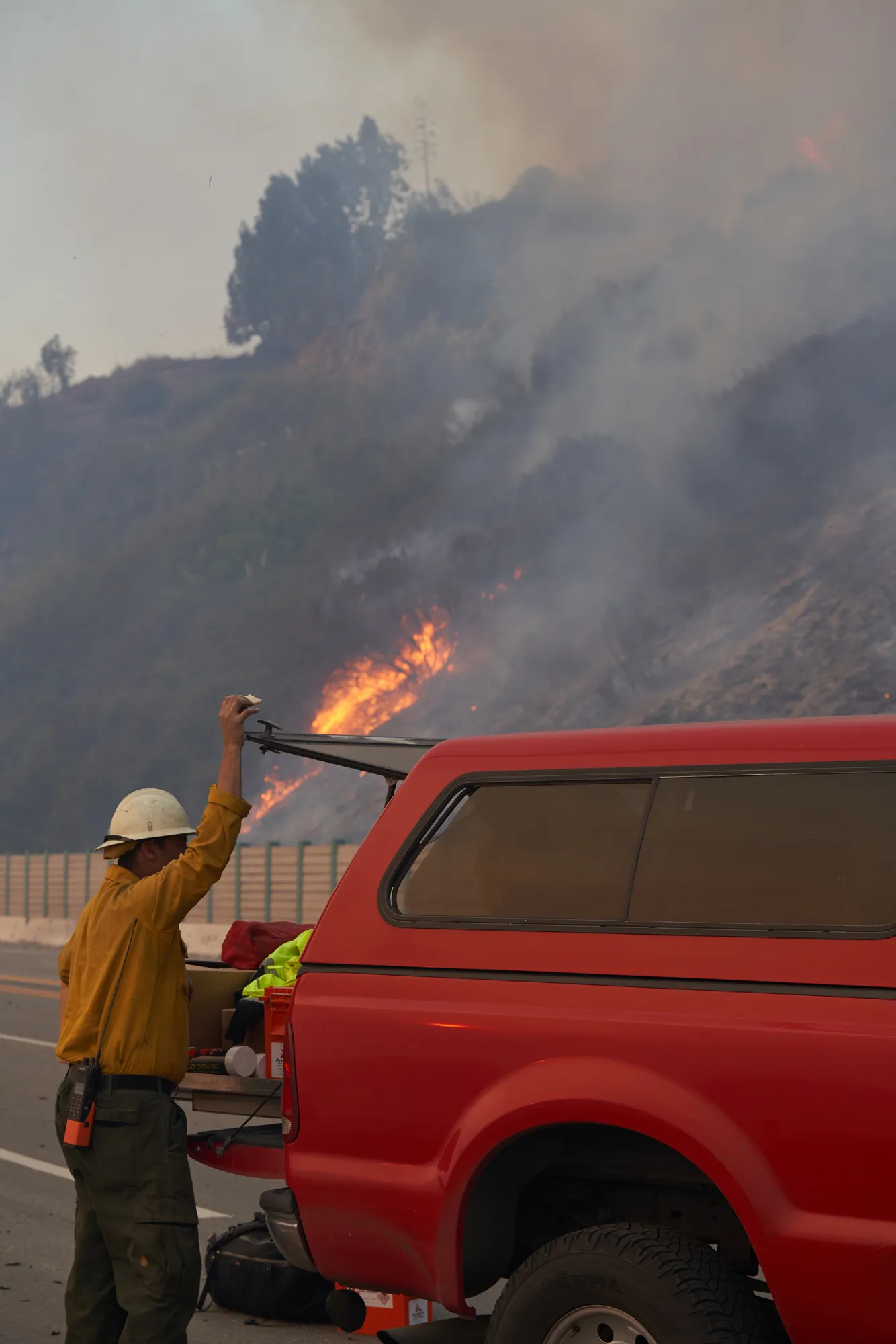 firefighter gathering gear to handle fire in the background