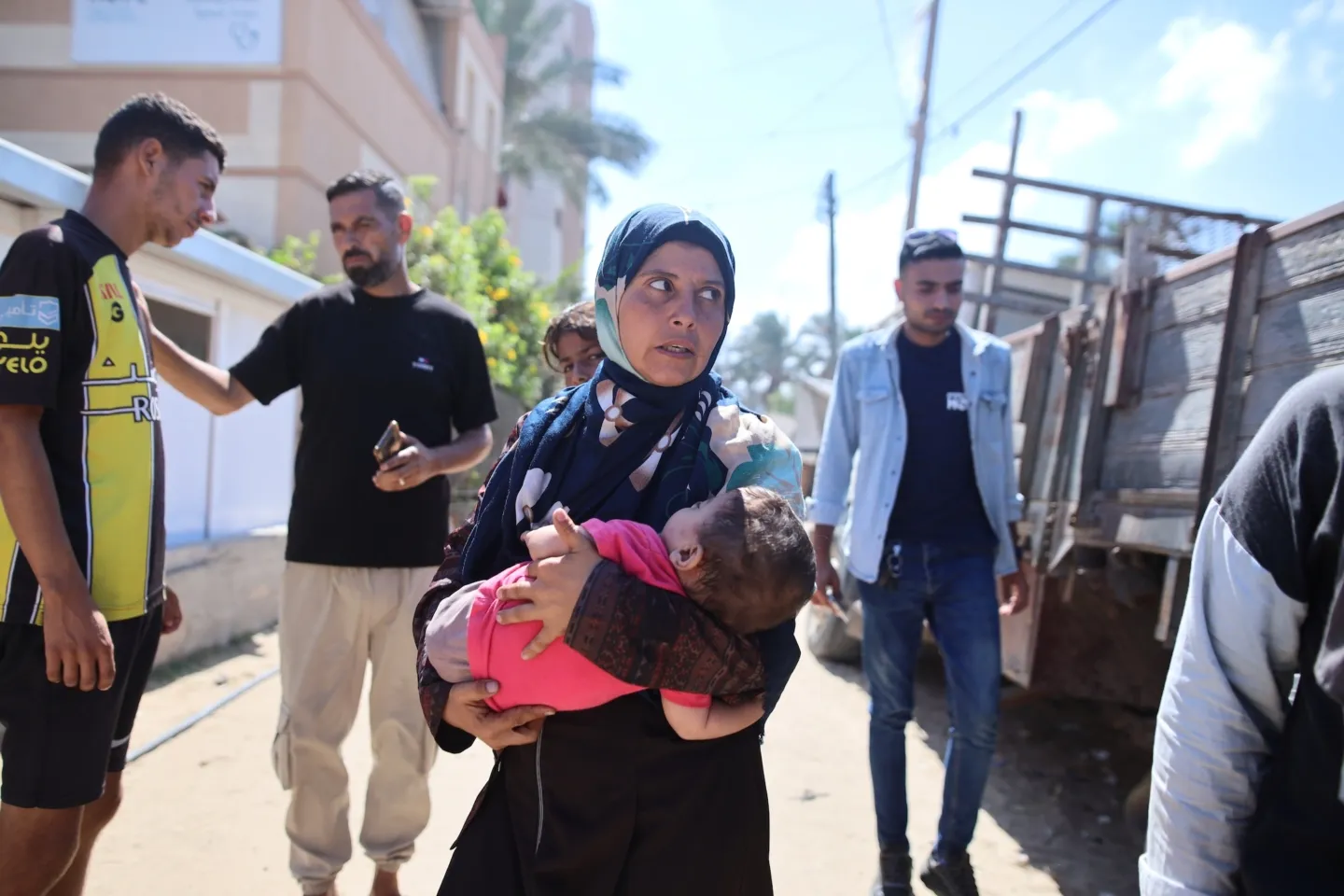 Mother carries child in Gaza outside medical clinic