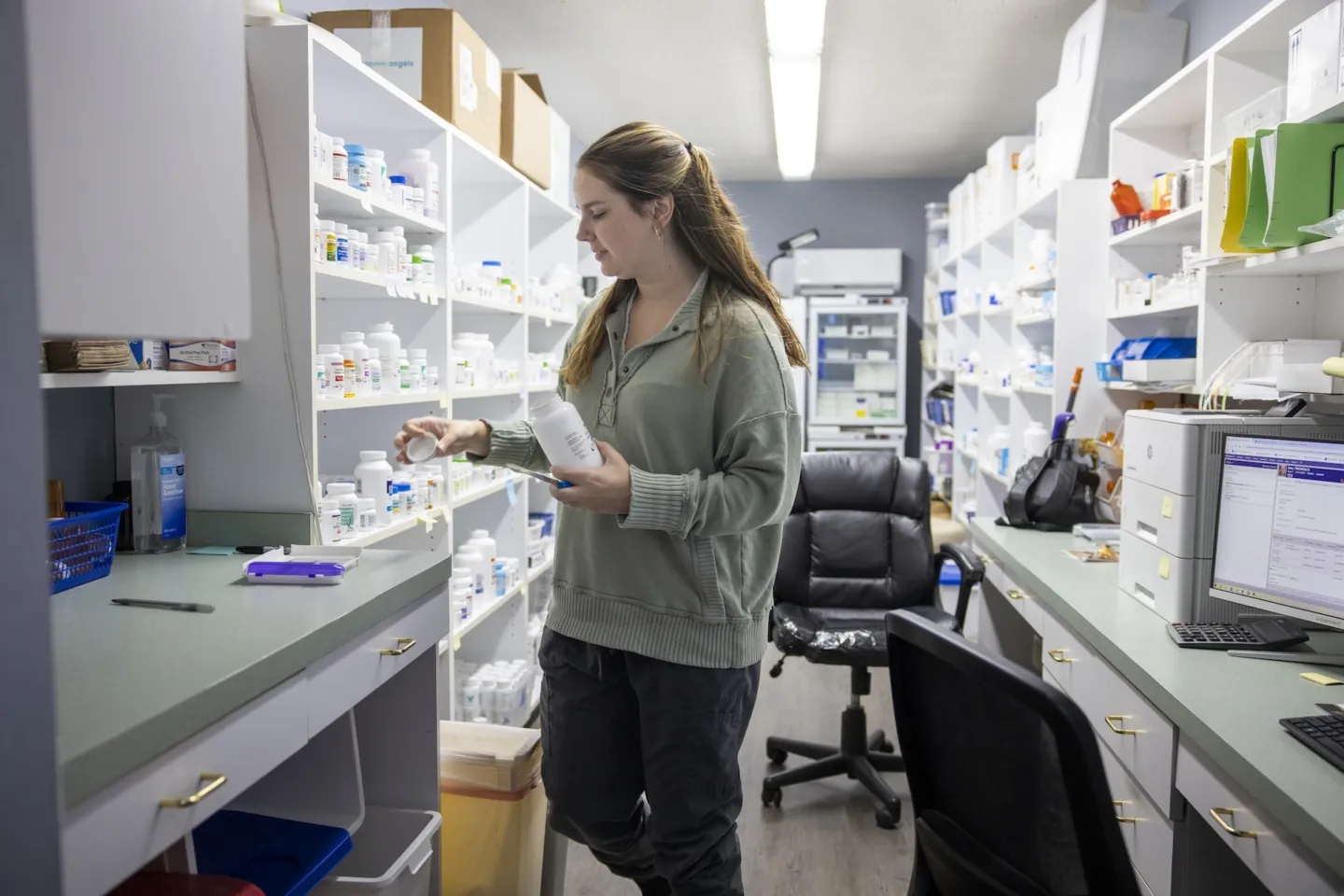 woman in green sweater collecting pharmaceutical supplies for patient in clinic