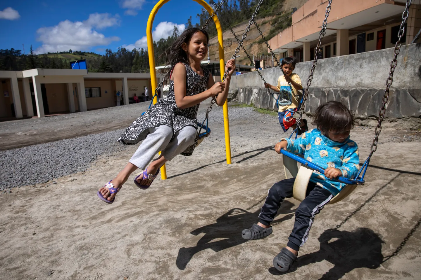 children swinging at a set in Ecuador