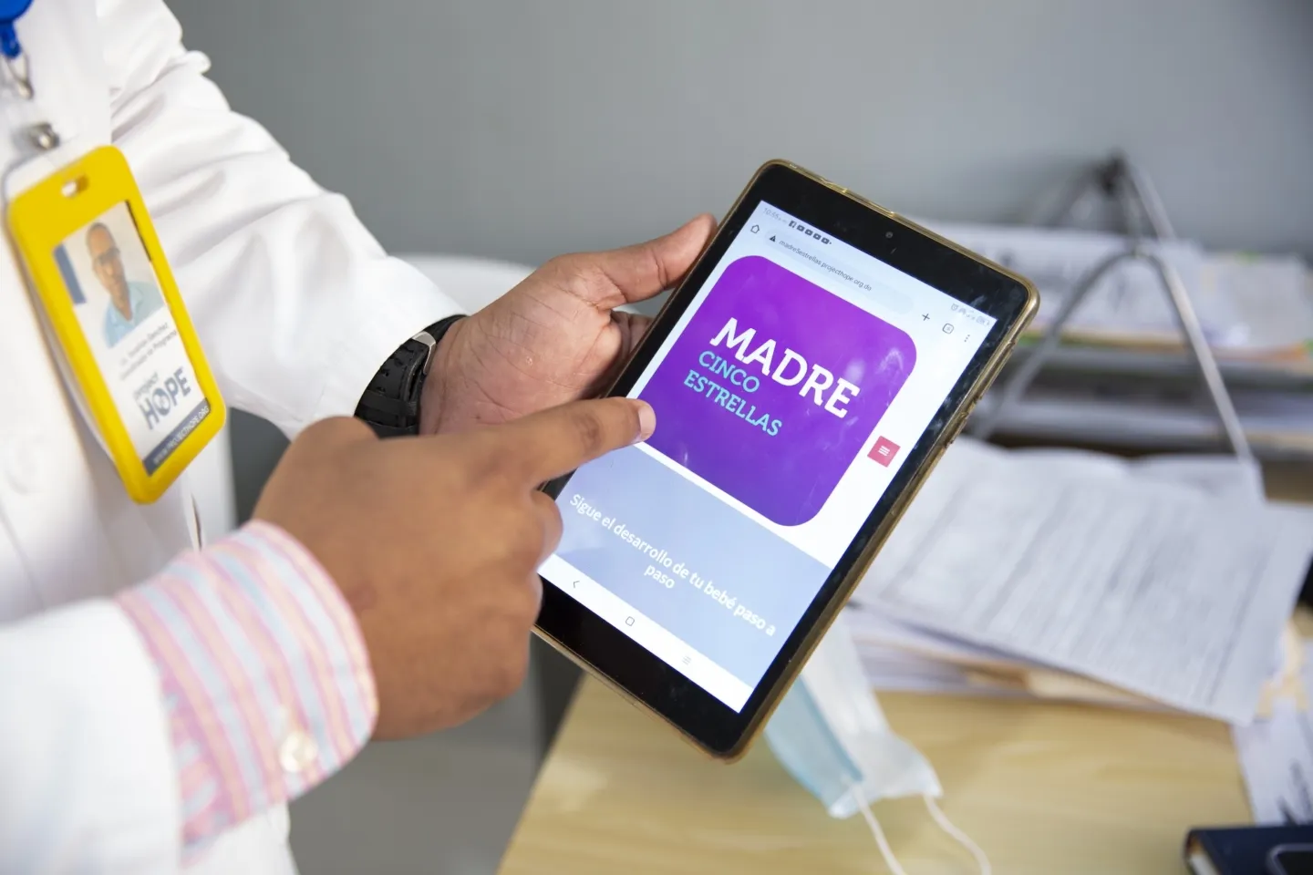 close up of a man holding a tablet with an app showing called "Madre Cinco Estrellas"