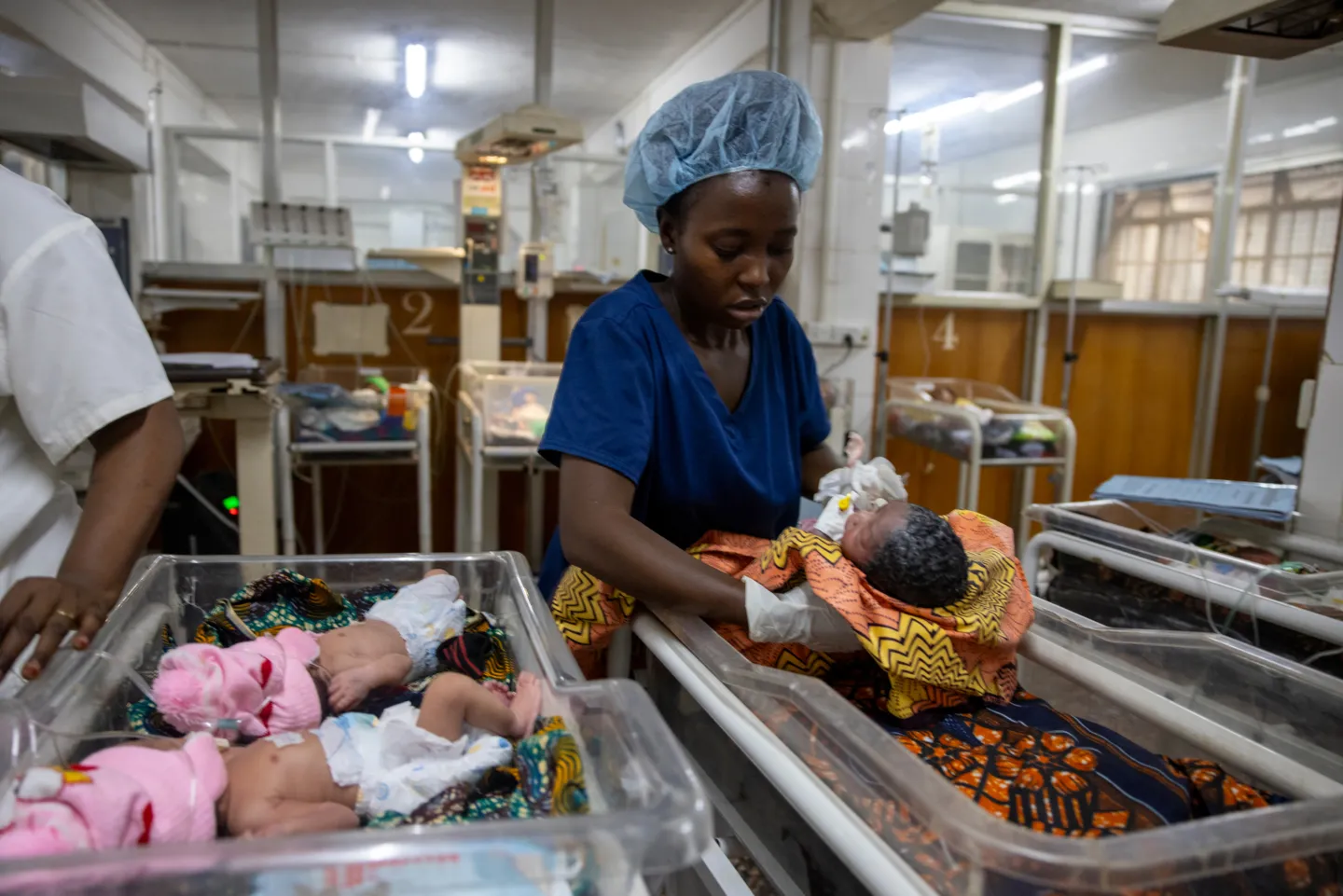 medical staff places newborn back into bed after check-up