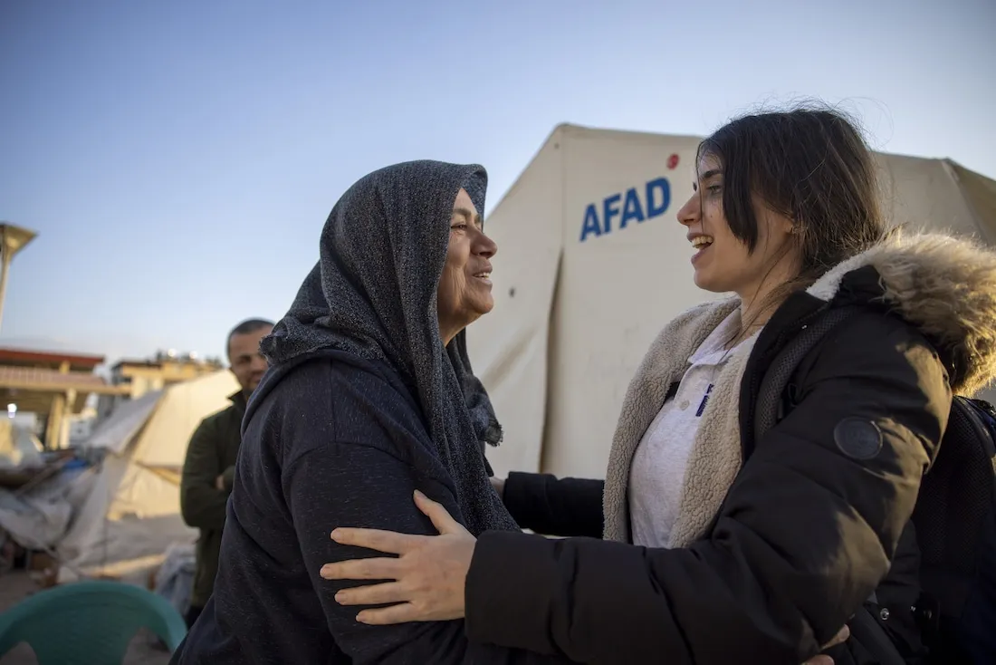 women hugging in front of tent