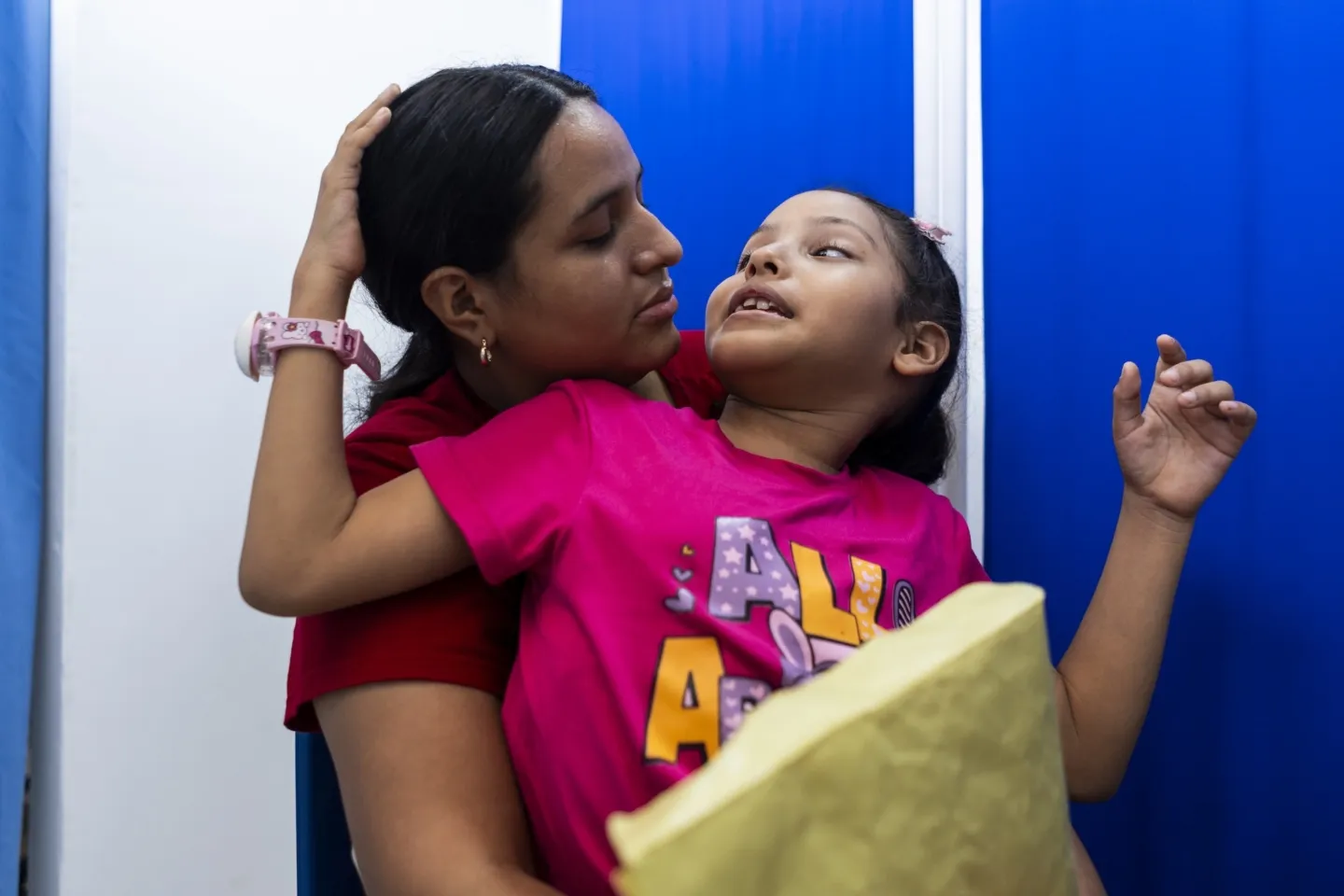 mother holds her young daughter as they look at each other