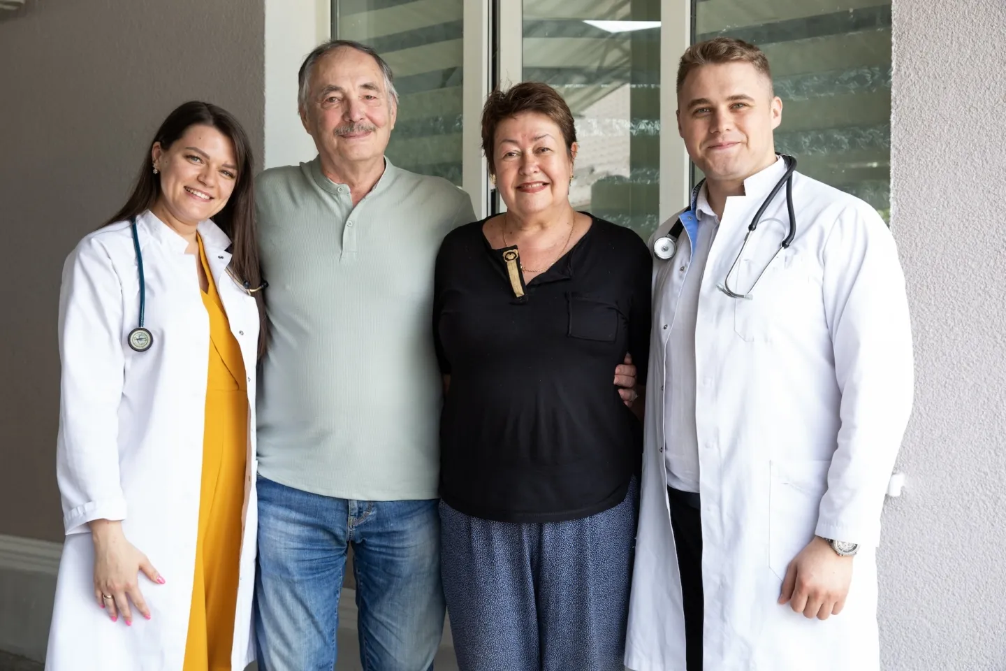 A female doctor, older man, older woman, and male doctor posing for a camera