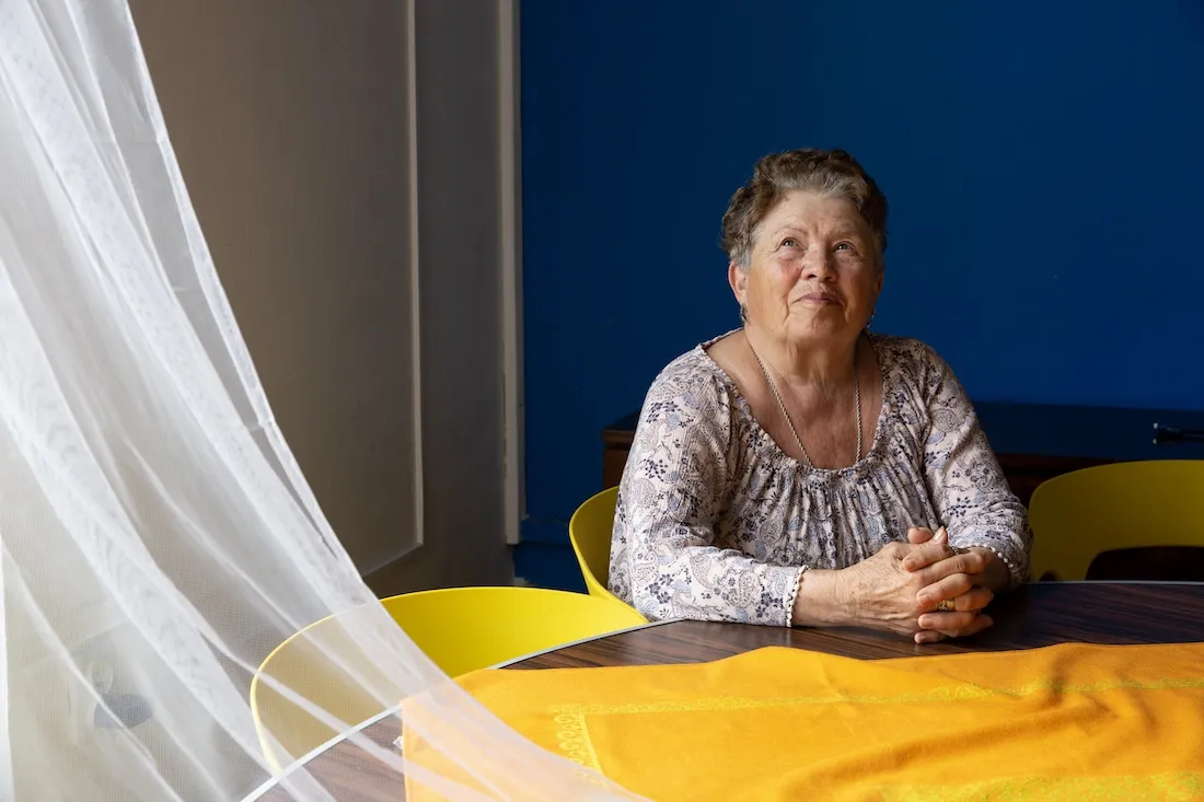 woman sits at table smiling towards light