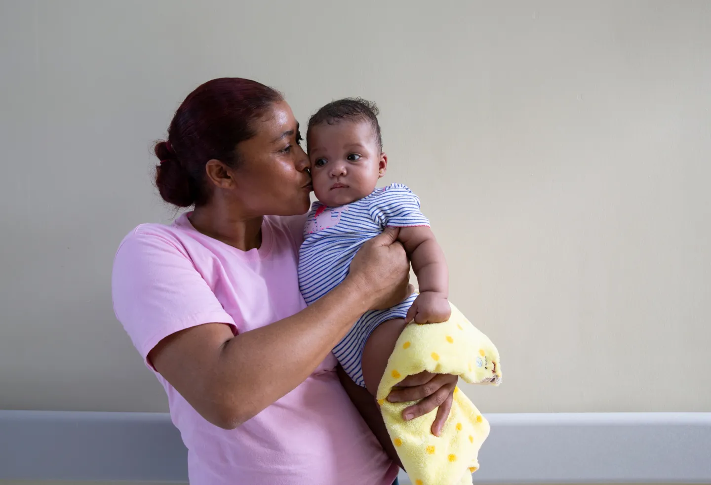 mother kisses temple of newborn baby