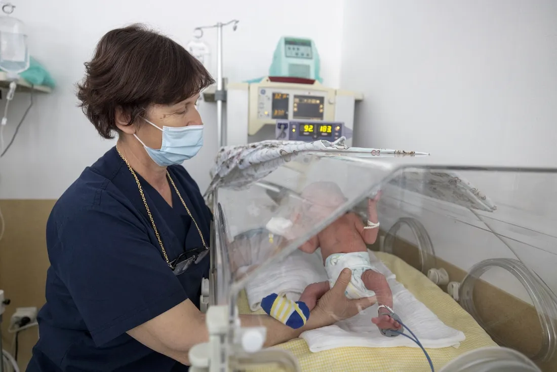 nurse checks on newborn in NICU
