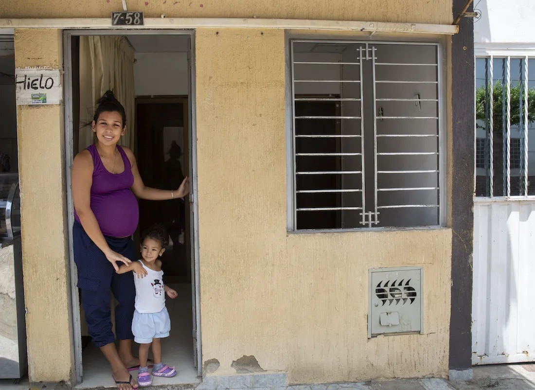 a mother and child standing in a doorframe smiling to the camera