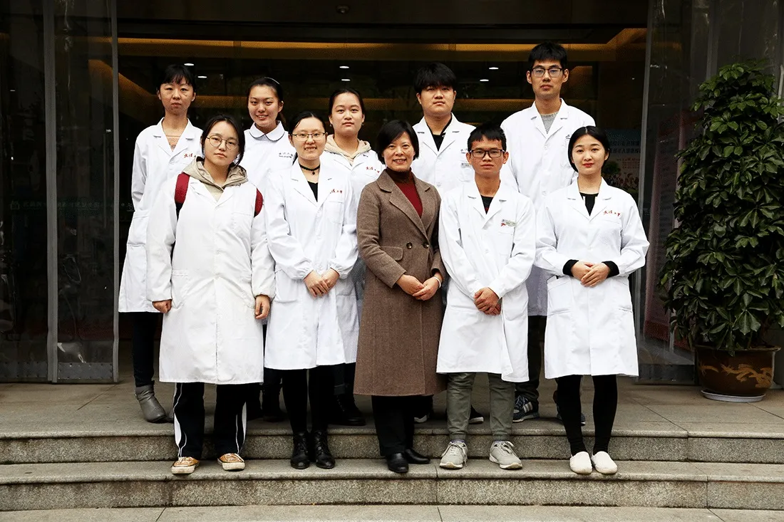 group of nursing students pose for picture in front of their school
