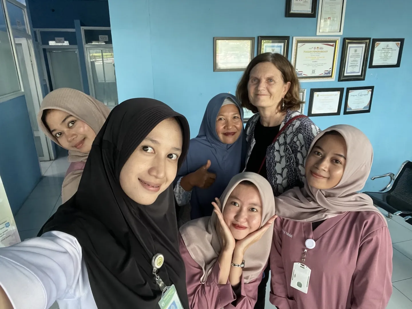 group of six women, five Indonesians midwives, pose for a selfie.