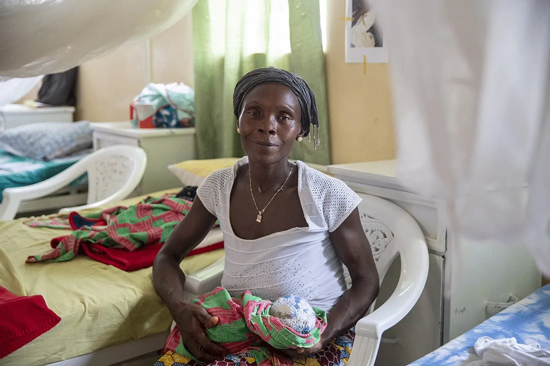 woman sitting down and holding a newborn
