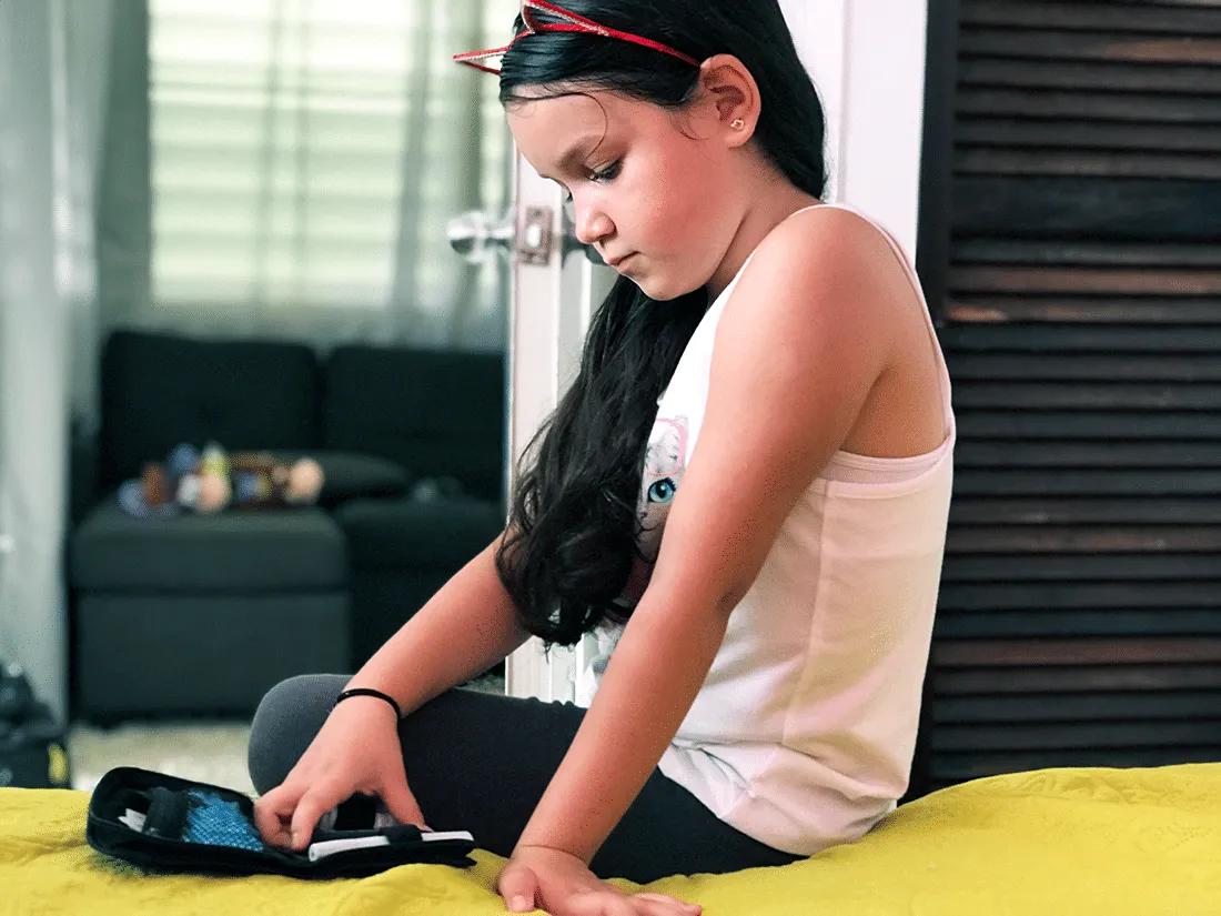 Young Nayeli sitting on her bed to get her insulin ready to take her medicine