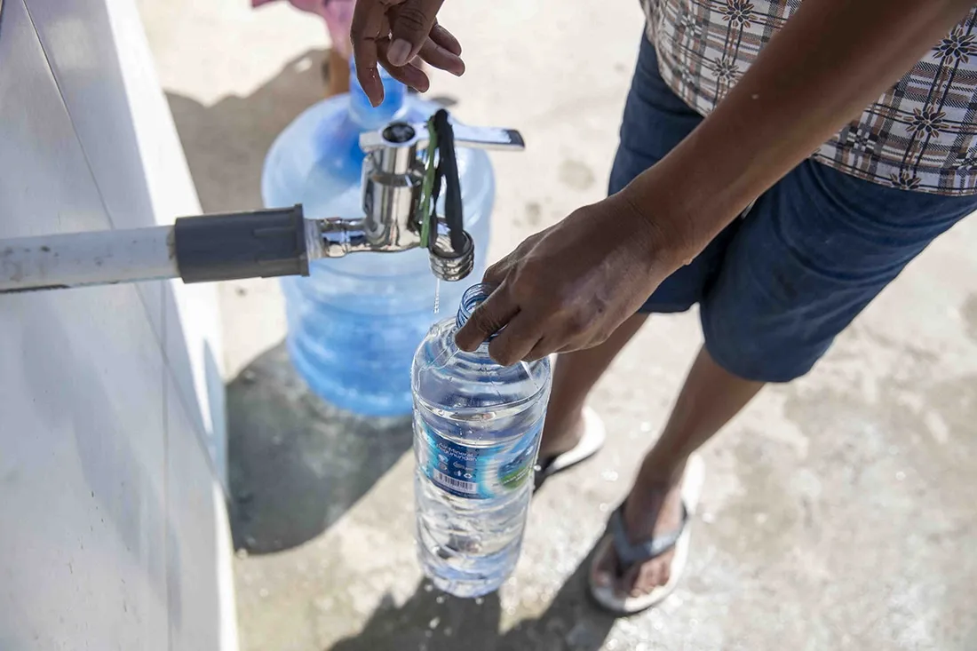 person filling water bottle with clean water