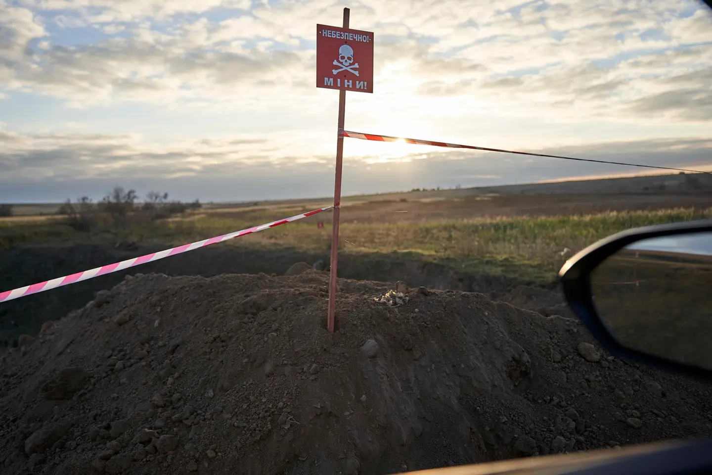 Sunset shot of a mound of dirt with a warning sign above it